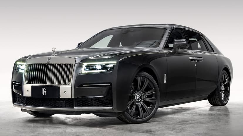Black Rolls-Royce Ghost sedan with glowing LED lights and dark wheels in a clean studio environment.
