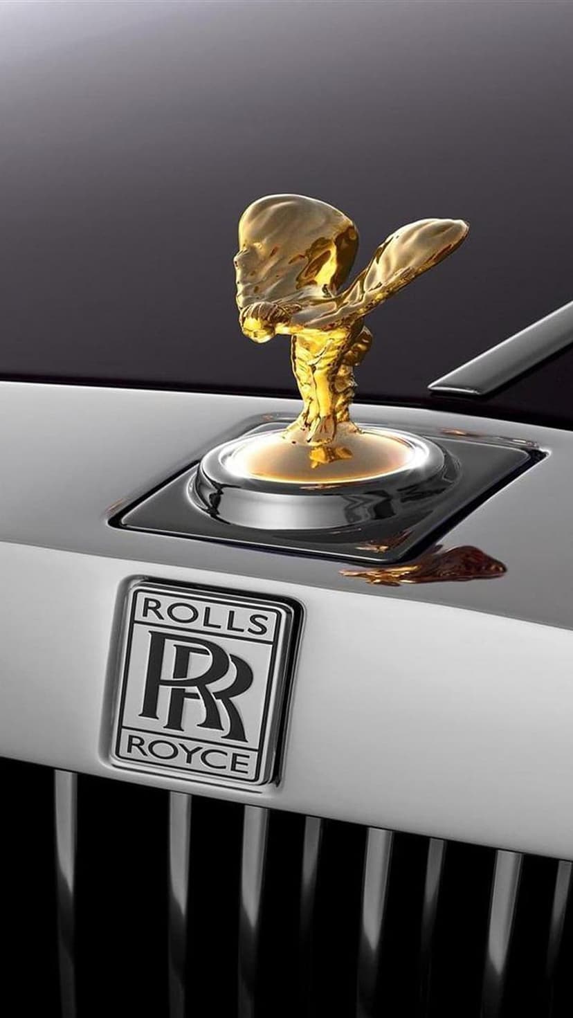 Golden Spirit of Ecstasy hood ornament and silver Rolls-Royce badge on a dark polished luxury vehicle.