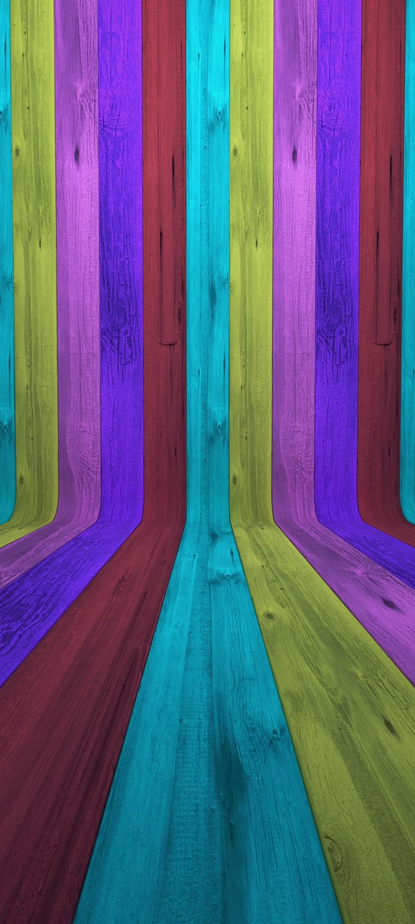 Vertical wooden planks in purple, red, and cyan curve inward to form a deep, colorful architectural tunnel.