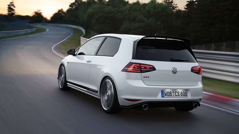 White Volkswagen Golf GTI Clubsport speeding around a curved track at dusk with glowing red taillights.