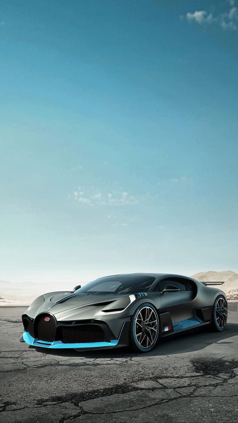 Dark grey Bugatti Divo hypercar parked on a dry desert road under a clear blue sky with distant mountains.