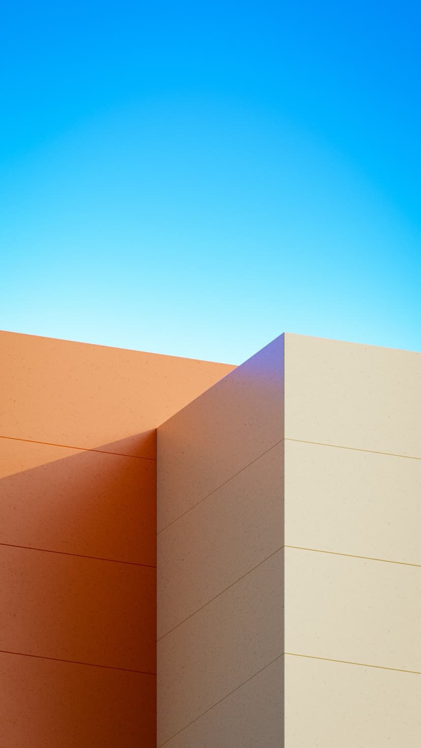 Orange and cream building corner intersects against a clear blue sky, showing clean architectural lines and shadows.