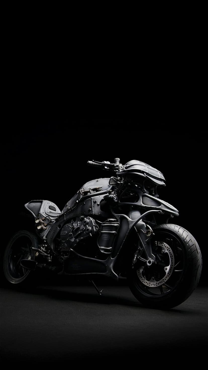 Matte black futuristic motorcycle with angular plating and exposed gears against a dark studio background.