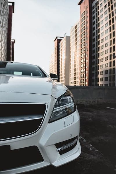 White Mercedes-Benz CLS parked with modern buildings background