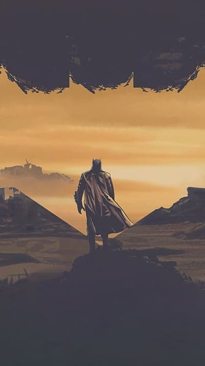 Batman stands silhouetted against a dramatic orange sky