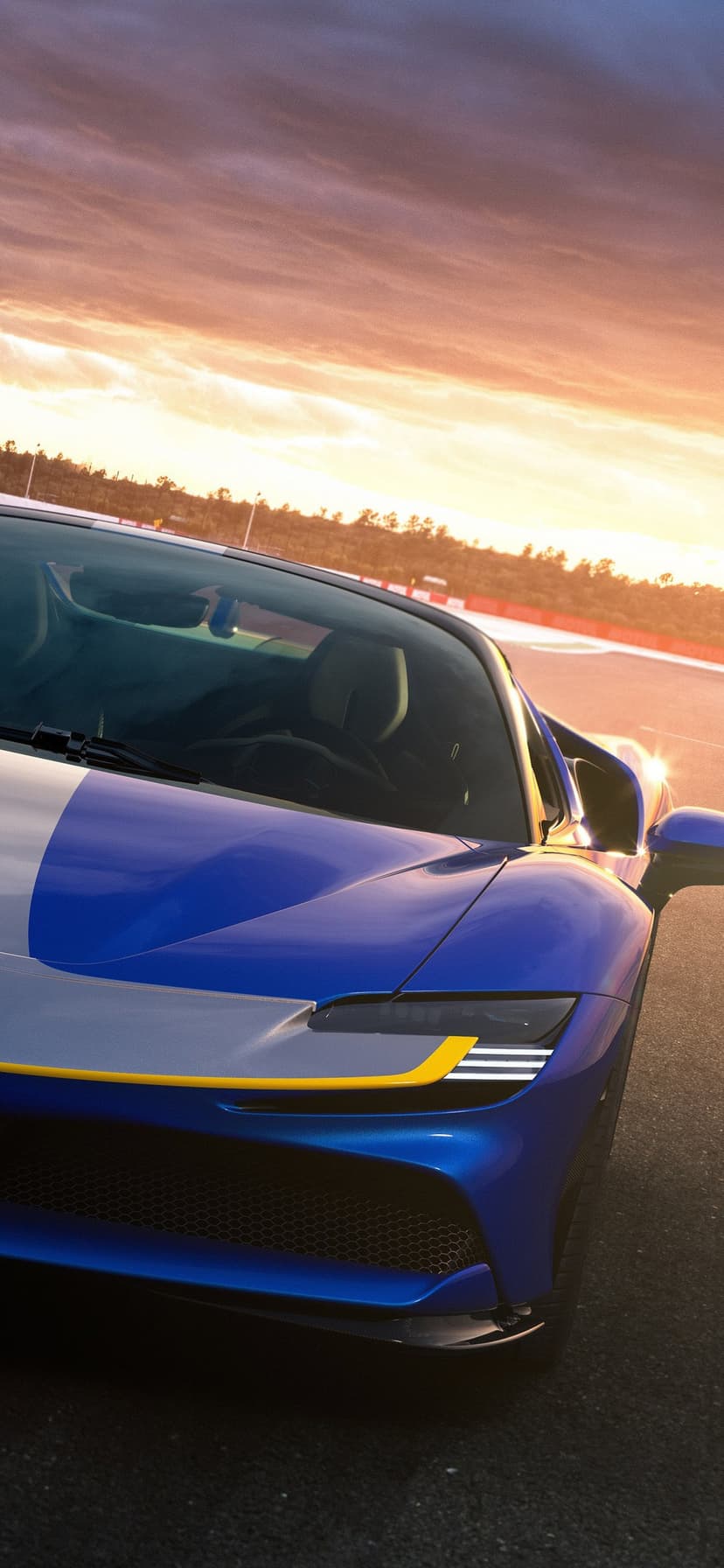 Blue supercar with silver and yellow accents parked on a track under a glowing sunset sky.