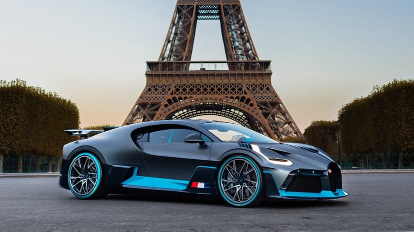Bugatti Divo hypercar with cyan accents parked before the Eiffel Tower in Paris under a clear evening sky.