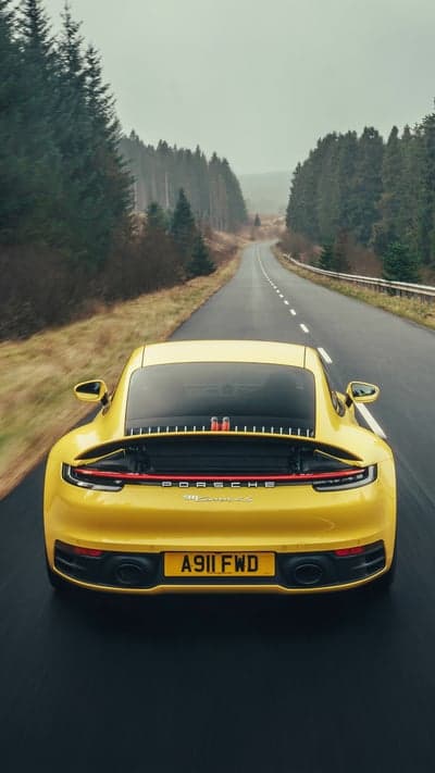 Yellow Porsche 911 Carrera 4S on Foggy Forest Road Wallpaper