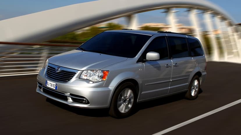 Silver minivan driving fast on a modern white arched bridge under a clear blue sky with cinematic motion blur.