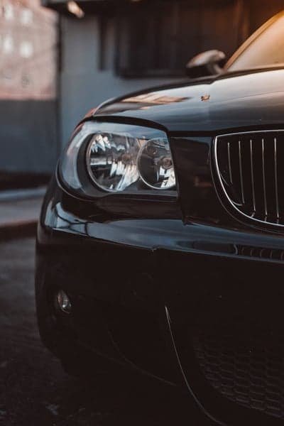 Close-up of a black car's front headlight and grille