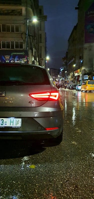 Rainy night street scene with car taillights and city lights