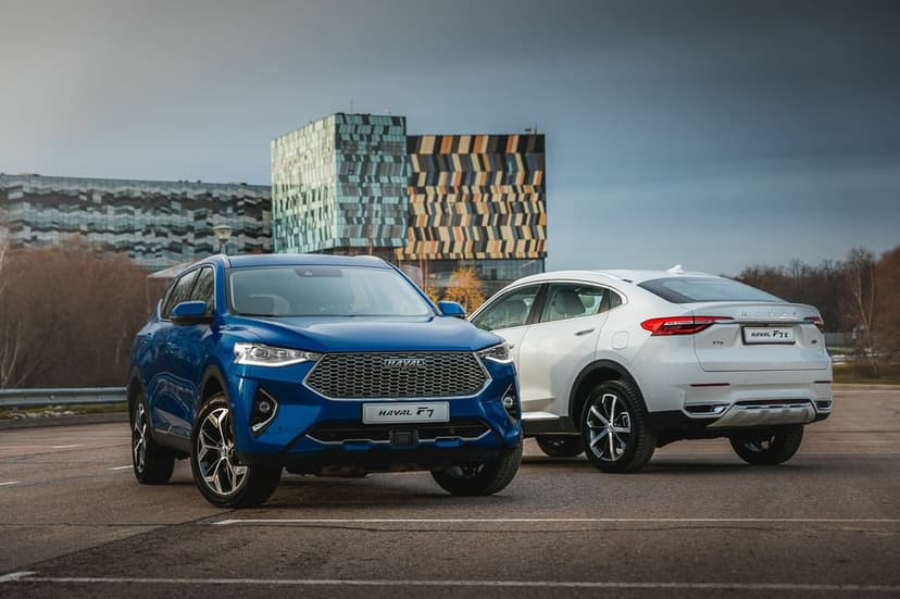 Blue and white Haval SUVs parked in a lot with modern geometric buildings and a cloudy sky background.