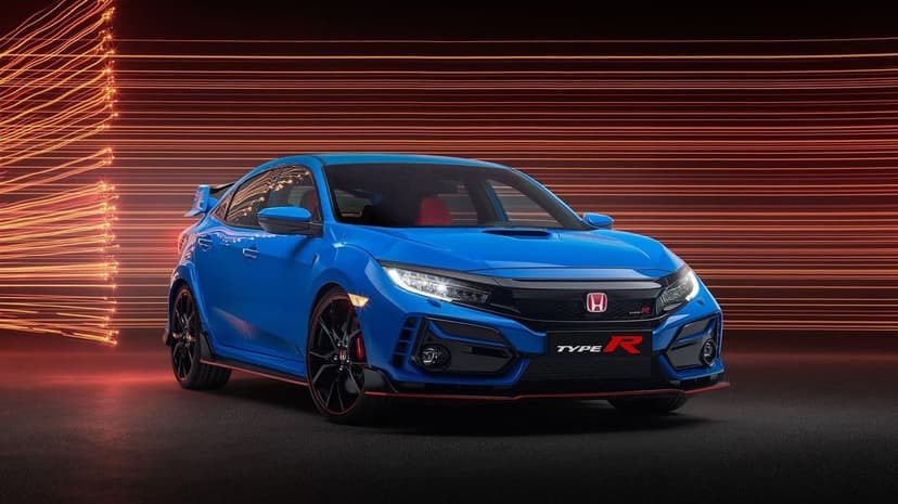 Blue Honda Civic Type R with glowing headlights against a backdrop of orange light trails in a dark studio.