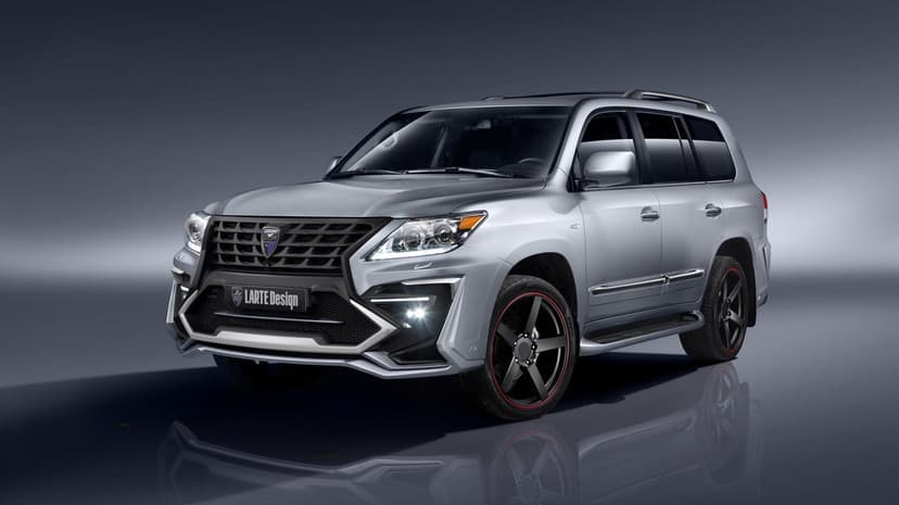 Silver luxury SUV with a black custom grille and black wheels with red accents in a dark studio setting.
