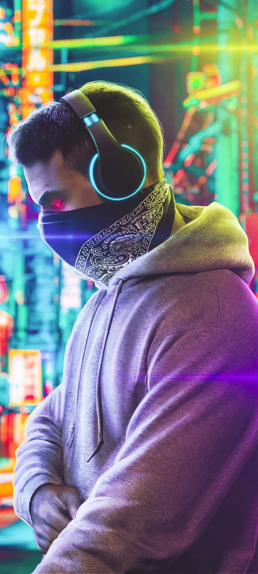 Man in a grey hoodie and paisley bandana with glowing red eyes and blue headphones in a neon-lit urban alleyway.