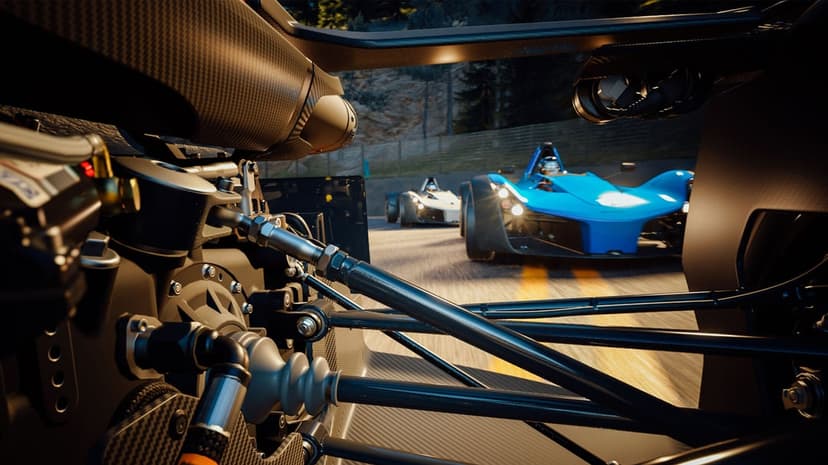 Mechanical suspension parts of a race car in foreground with a blue open-wheel car on a track behind.