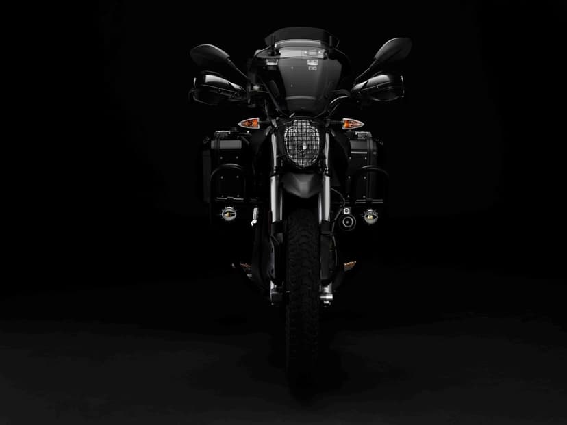 Front view of a black adventure motorcycle with auxiliary lights against a solid black studio background.