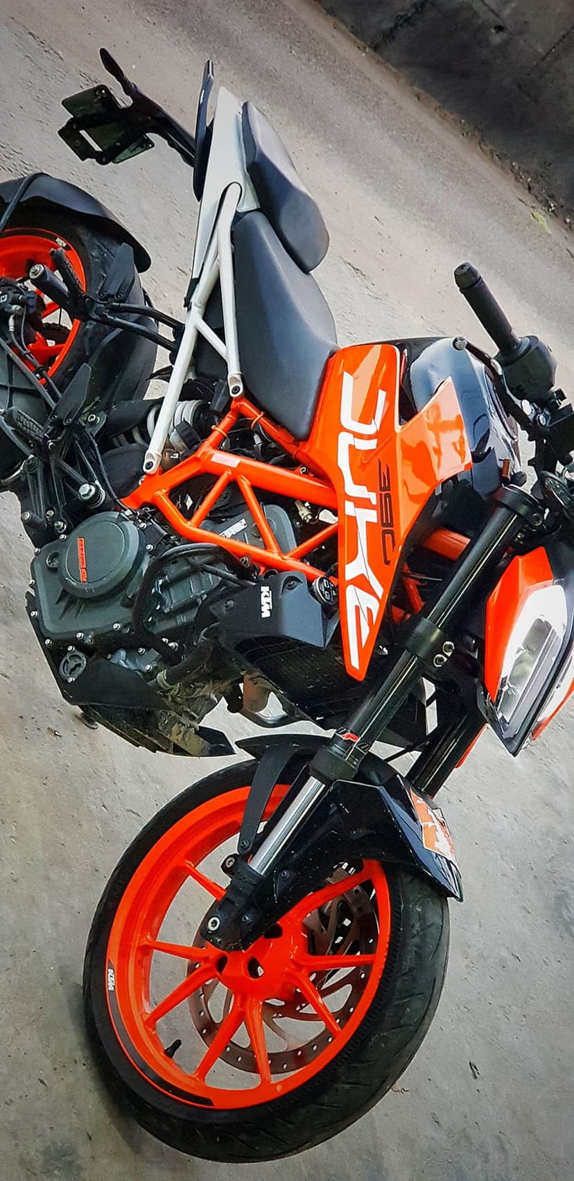 KTM 390 Duke motorcycle featuring bright orange wheels, black engine components, and aggressive trellis frame.