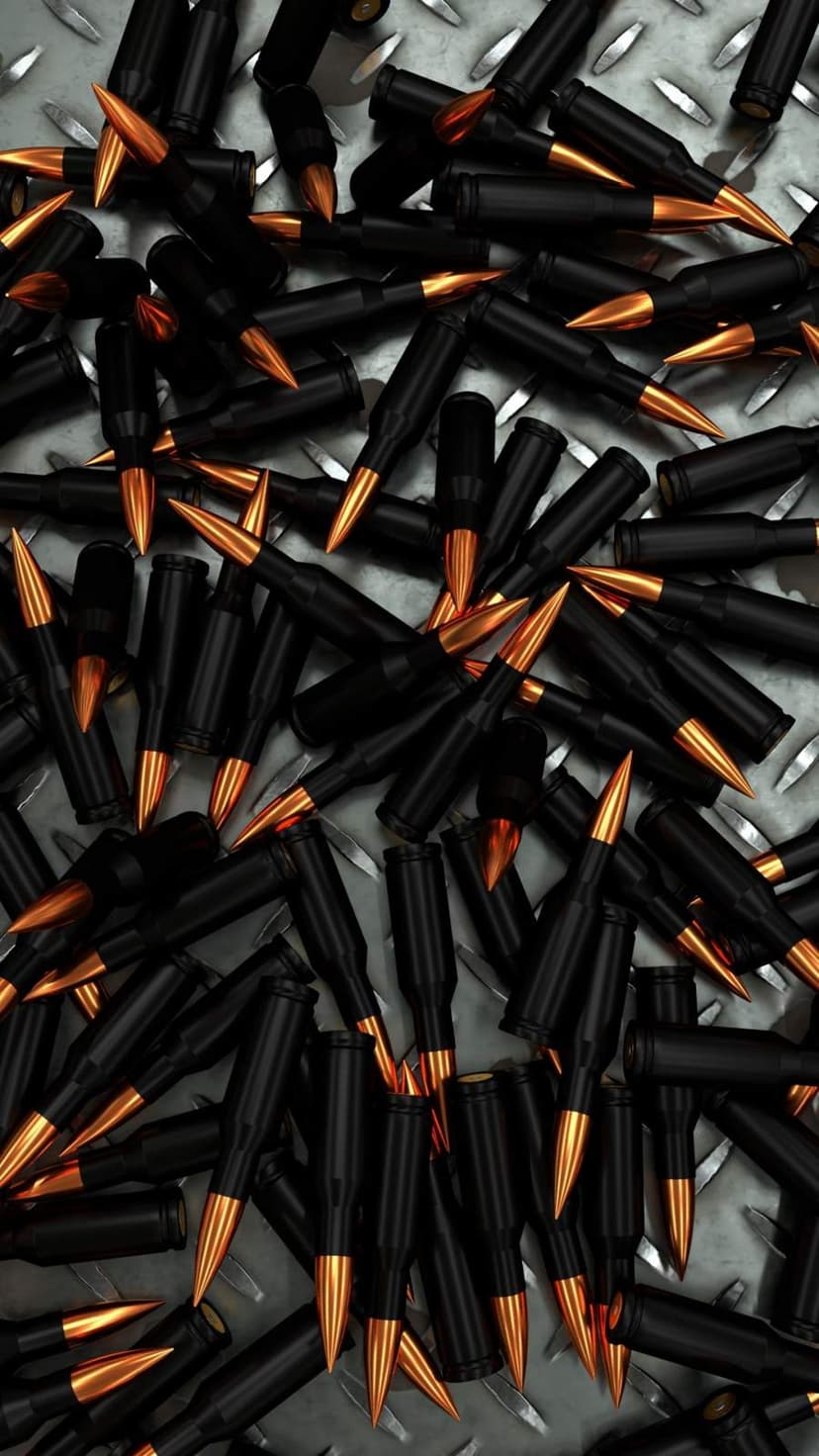 Black bullet casings with gold tips scattered across a textured silver diamond plate metal surface in macro view.