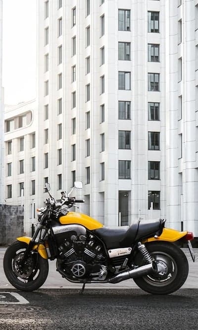 Yellow Yamaha VMAX motorcycle parked against modern building
