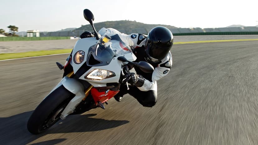 BMW S1000RR sportbike and rider leaning deep into a racetrack curve with intense motion blur.