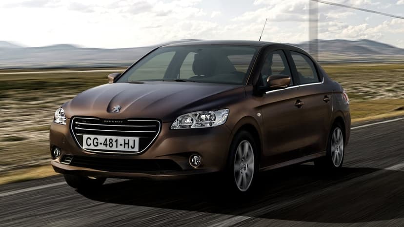 Brown Peugeot sedan driving fast on an asphalt road with blurred mountains and a cloudy sky in the background.