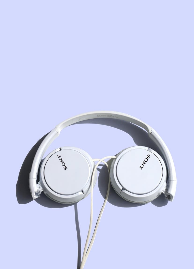 White Sony headphones centered on a light purple background with soft shadows and visible logo on the earcups.