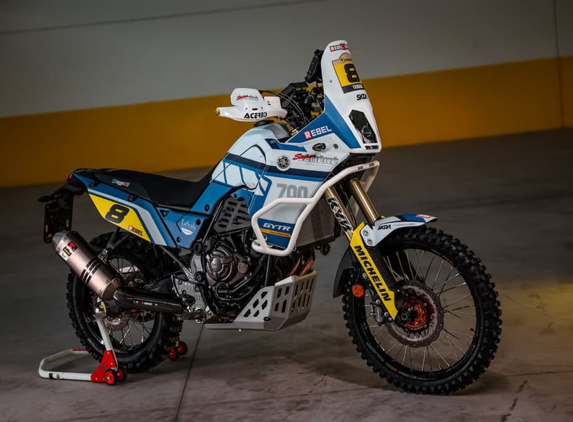 Yamaha Tenere 700 rally motorcycle with blue and white graphics on a stand against a yellow and white wall.