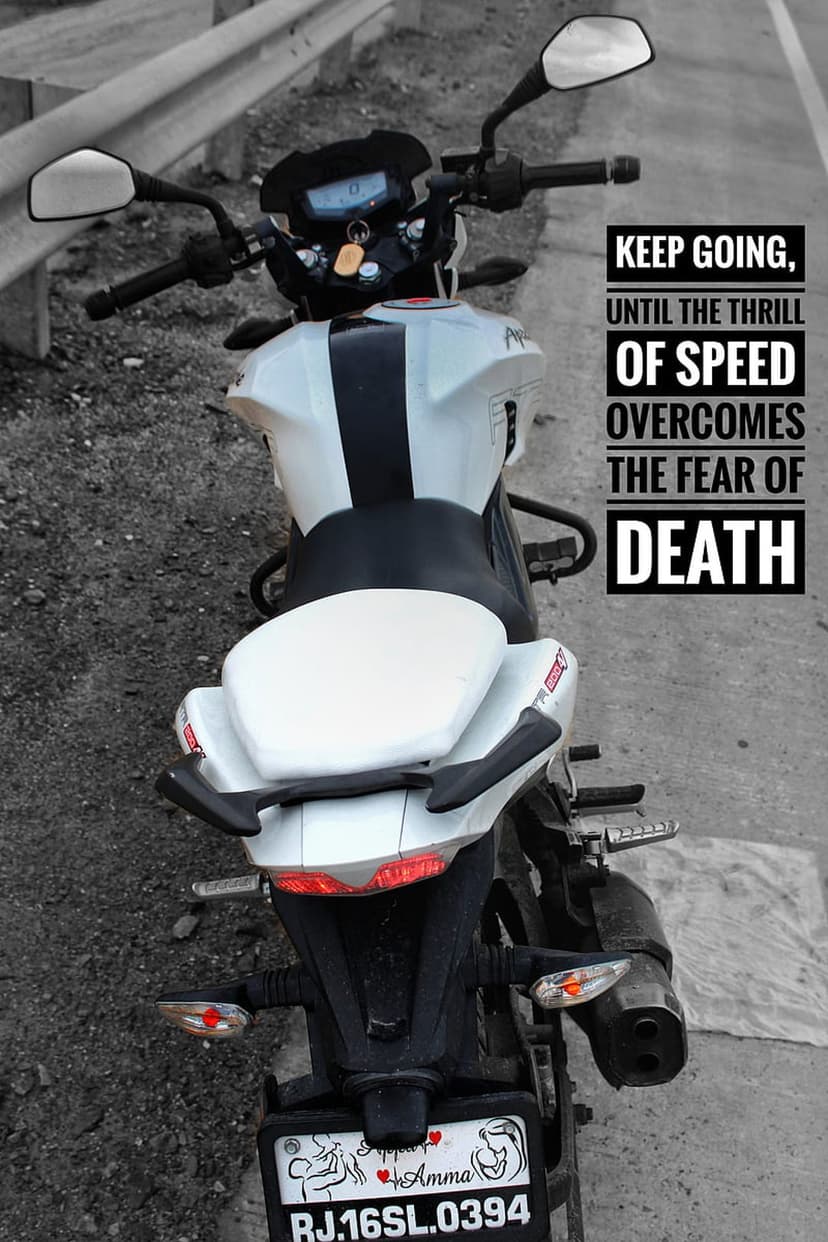 White Apache motorcycle with glowing taillights and text reading keep going until the thrill of speed overcomes fear.