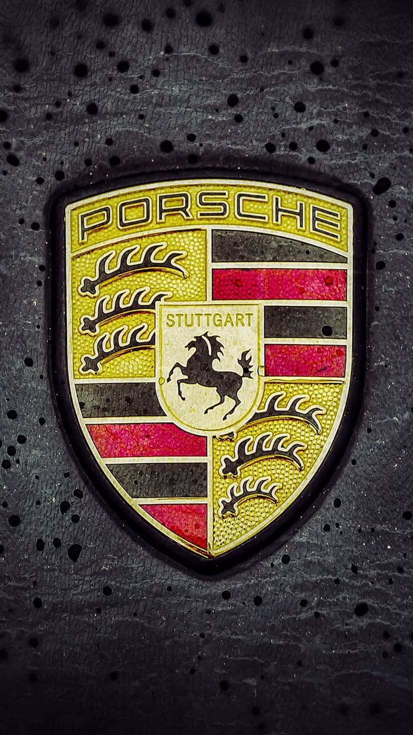 Porsche crest with a rampant horse and gold accents centered on a dark textured background with red details.