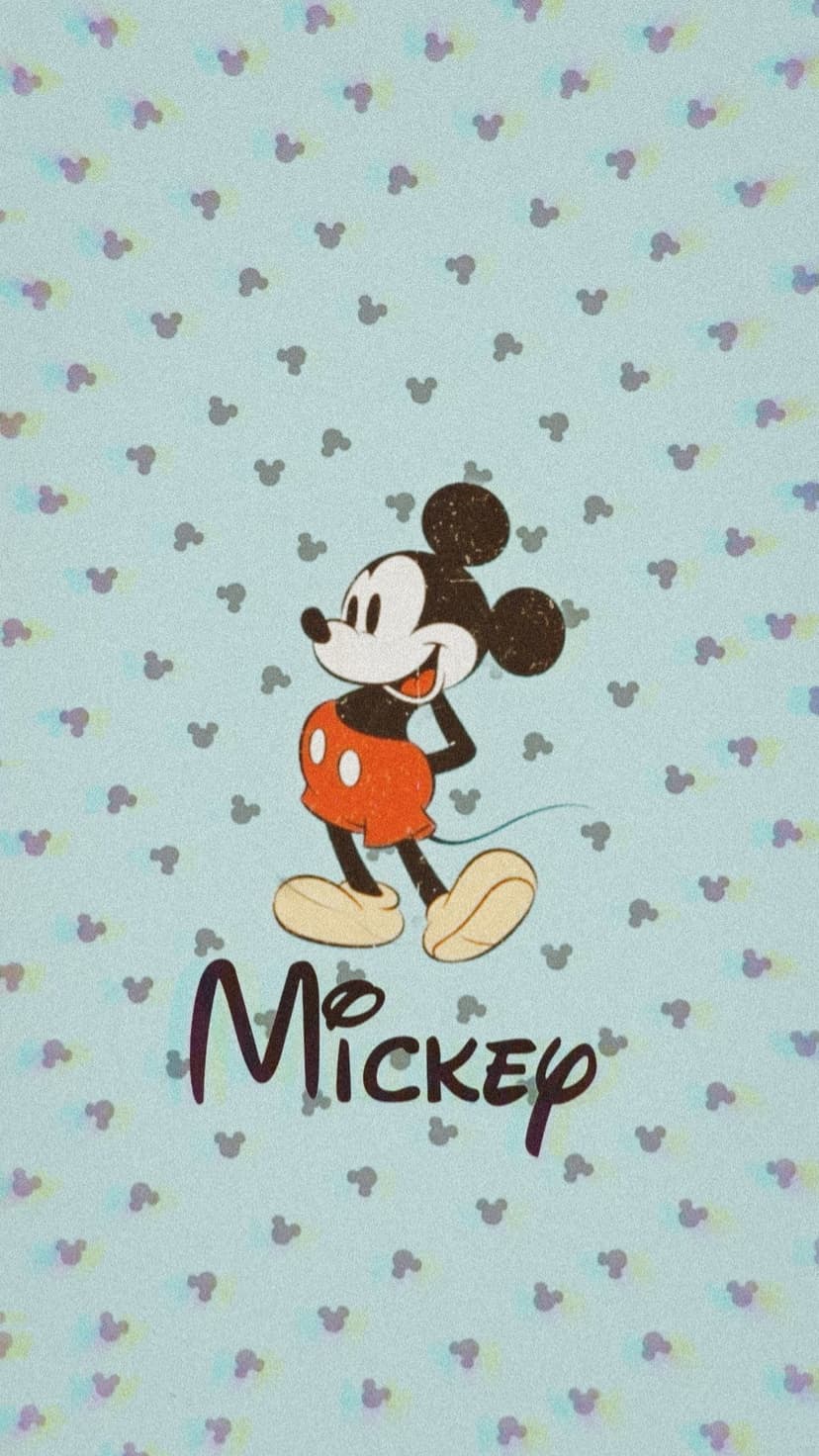 Mickey Mouse in red shorts and yellow shoes stands against a blue textured pattern of small mouse head icons.