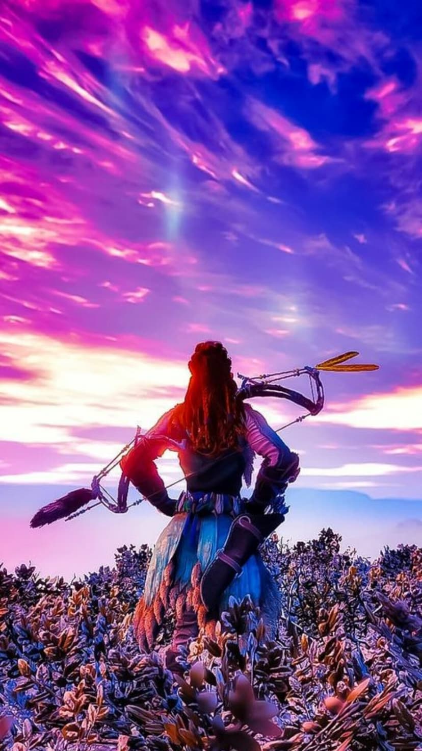 Aloy with a bow on her back stands in a field of purple flowers under a vibrant magenta and blue sunset sky scene.