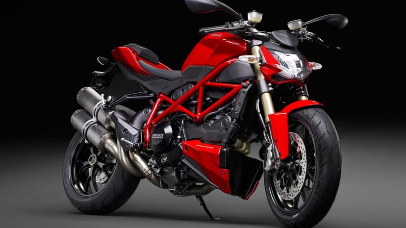Red Ducati Streetfighter motorcycle with a trellis frame and gold forks against a dark studio background.