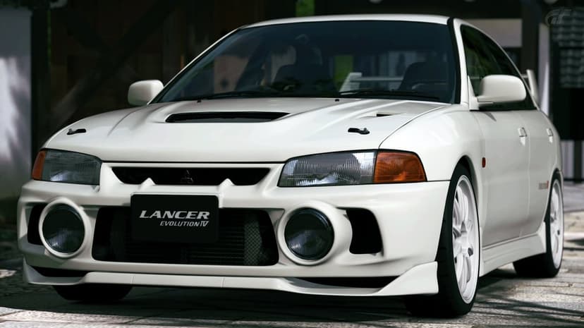 White Mitsubishi Lancer Evolution IV sports car with large fog lights and white wheels on a paved road.