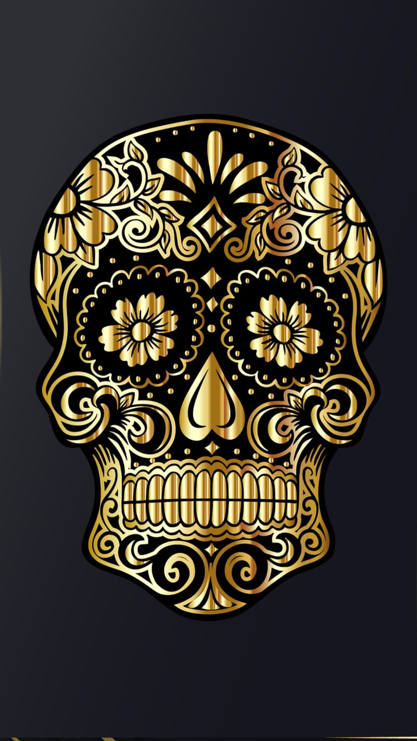 Ornate golden sugar skull with metallic floral filigree and detailed mandible set against a dark background.