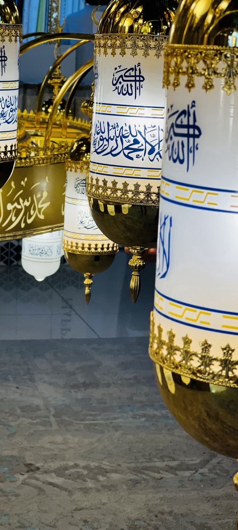 Ornate Islamic lanterns featuring gold patterns and blue Arabic calligraphy glowing in a sacred Medina setting.