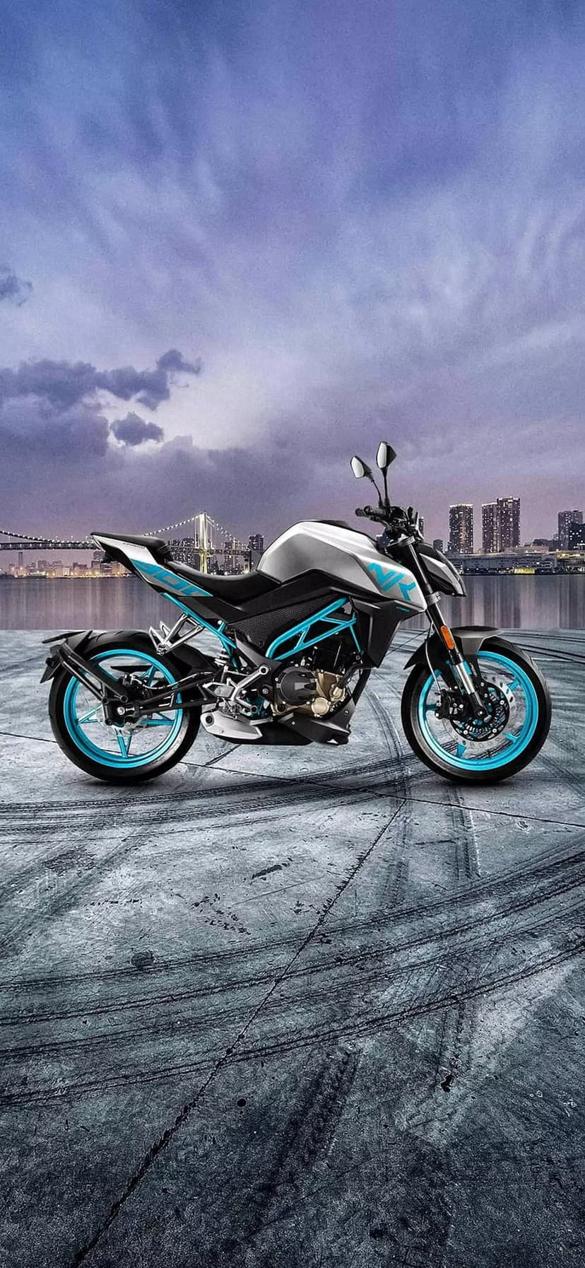 Blue-accented sportbike parked on asphalt with tire marks before a twilight cityscape and cloudy skyline.
