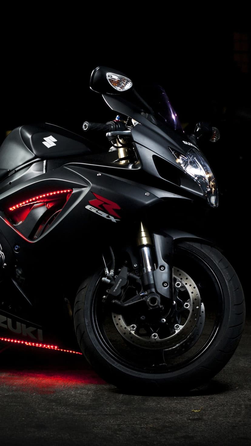 Suzuki GSX motorcycle featuring red LED lighting on the fairing and front wheel against a dark backdrop.