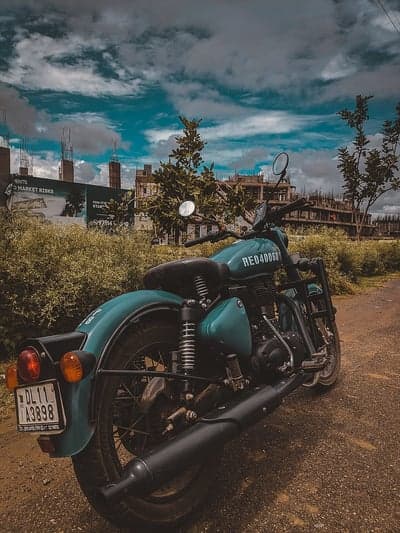 Teal motorcycle parked by construction site, dramatic clouds
