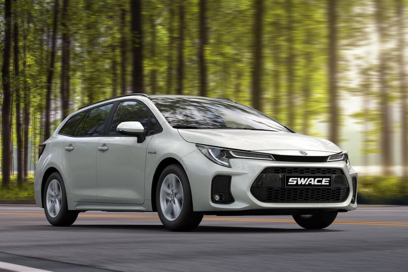 White Suzuki Swace station wagon driving on a paved road with motion-blurred trees in the background.