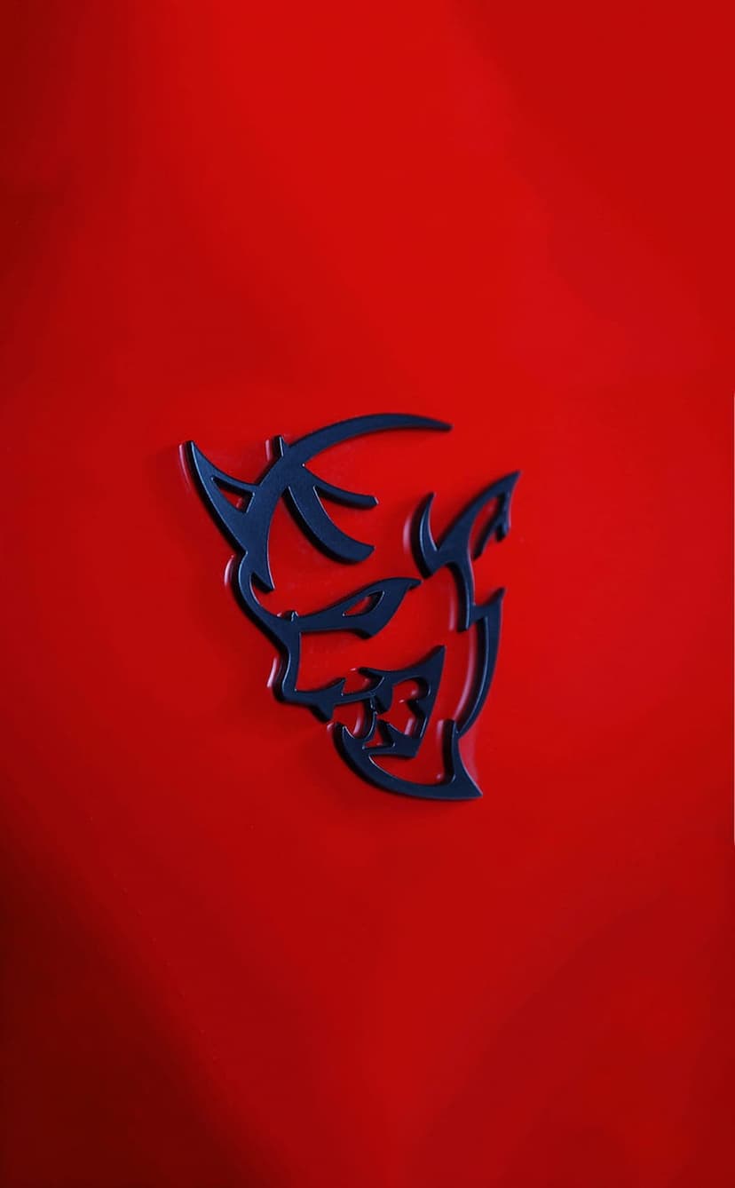 Hellcat logo in dark blue on a textured red background with sharp lines and aggressive automotive styling.
