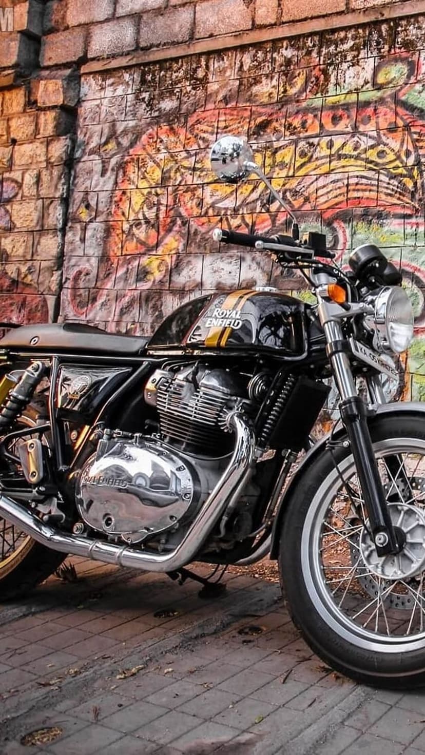 Royal Enfield Interceptor 650 motorcycle with chrome engine details parked against a colorful graffiti brick wall.