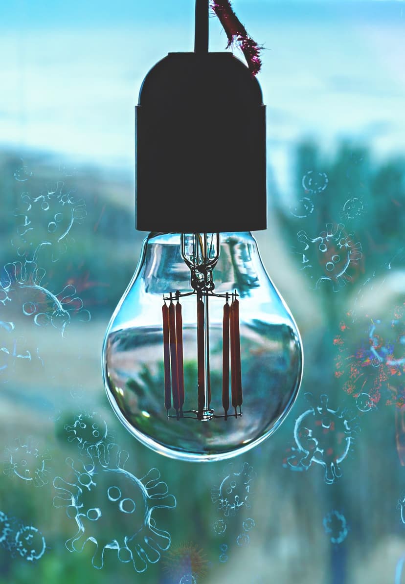 Vintage light bulb with glowing filaments surrounded by translucent spherical virus particles on a dark background.