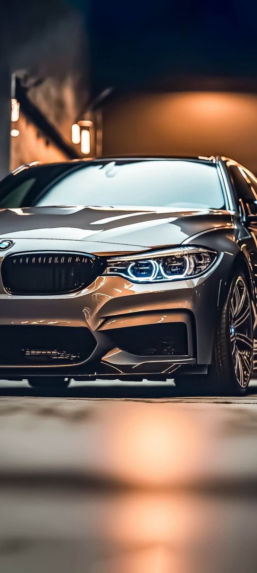BMW M car front view featuring a black kidney grille and glowing blue LED headlights against a dark background.