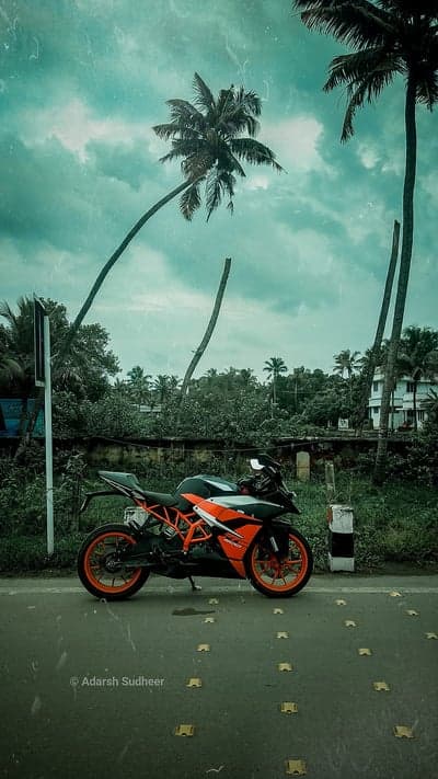 Orange KTM Motorcycle parked by the road with palm trees