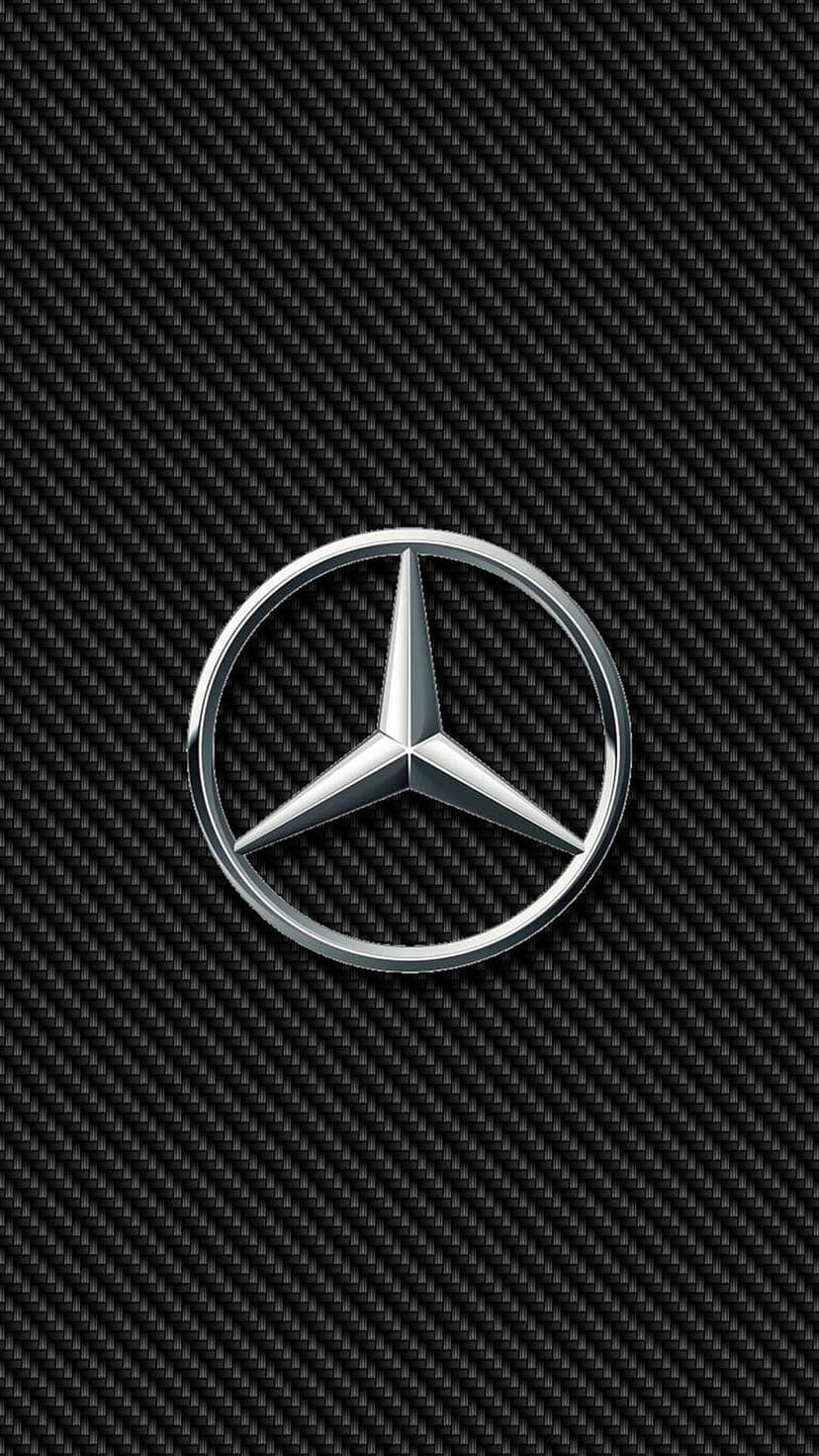 Polished chrome Mercedes-Benz star emblem centered on a textured black carbon fiber weave pattern background.
