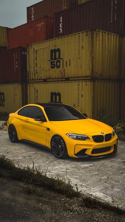 Yellow BMW M2 Coupe parked by shipping containers