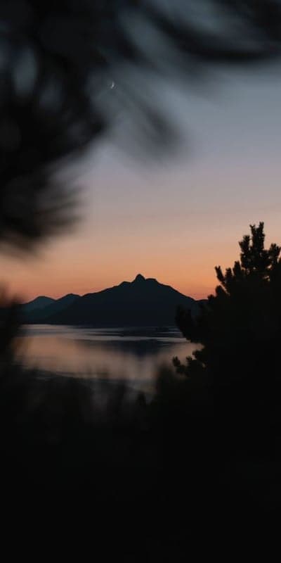 Dawn's Embrace - Mountain Silhouettes Over Calm Waters