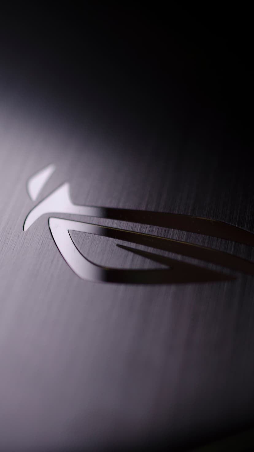 ROG logo engraved on a dark brushed metal surface with a soft light gradient across the industrial texture.