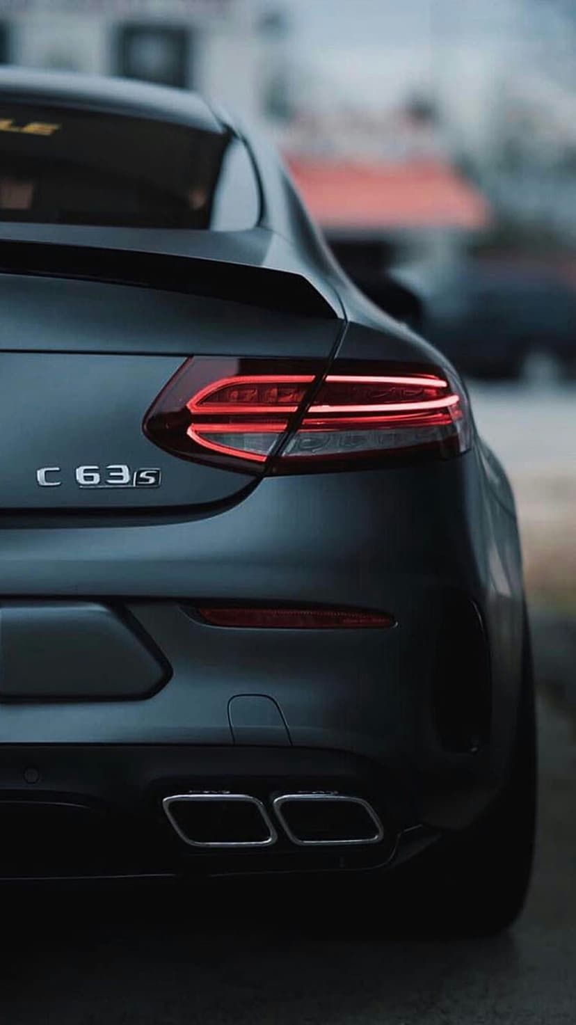Mercedes-AMG C 63 S rear badge and LED taillights on a dark gray coupe with quad chrome exhaust pipes.